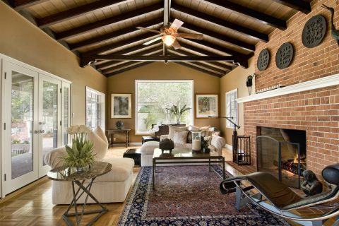 Beautiful living room with large brick fireplace, area rug, fan, french doors, windows and expensive furnishings, wood floor